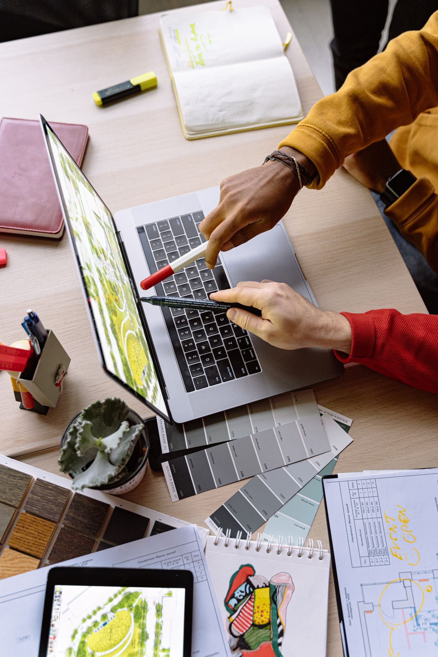 Designers reviewing cover artwork on a laptop screen alongside printed colour swatches