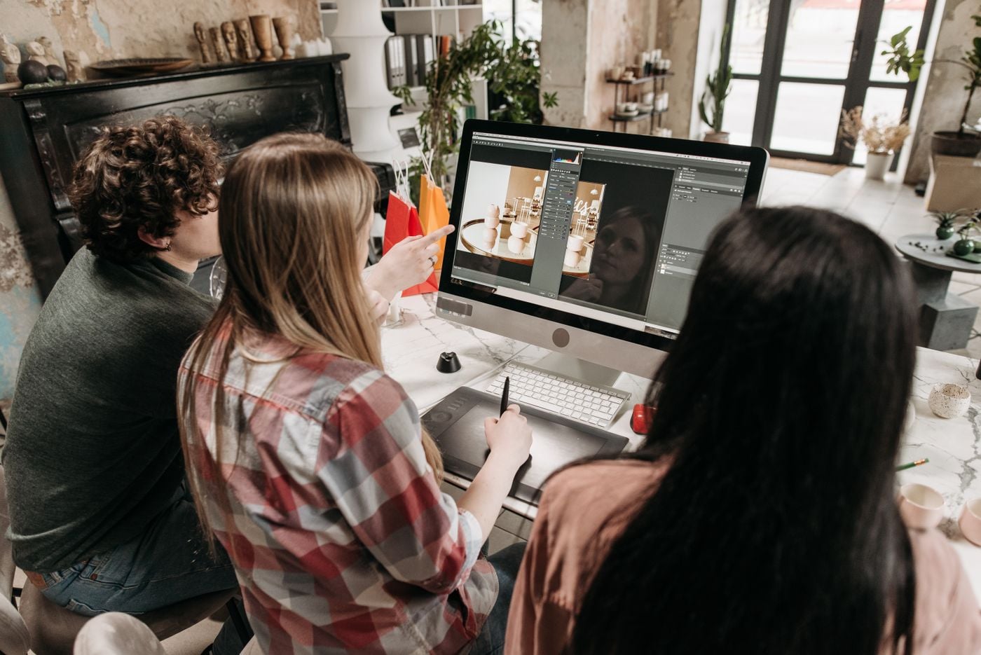 Designers reviewing layout and image work on a large monitor in a design studio